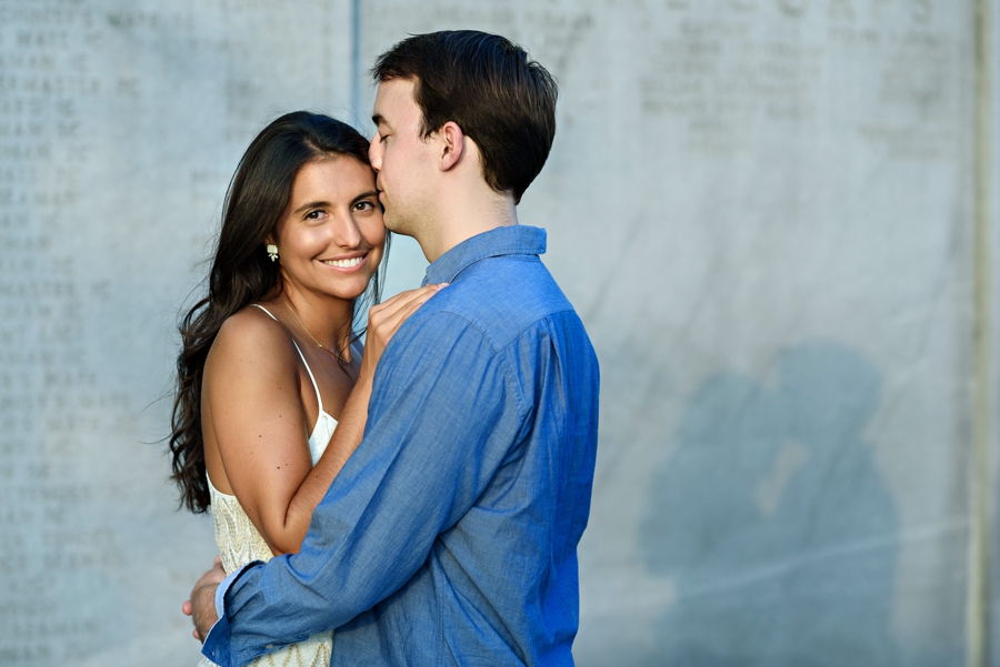 A beautiful couple embrace in the setting sunlight in battery park during their NYC engagement.